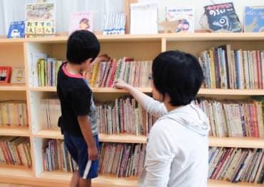 本棚から本を選ぶ子どもたちの写真
